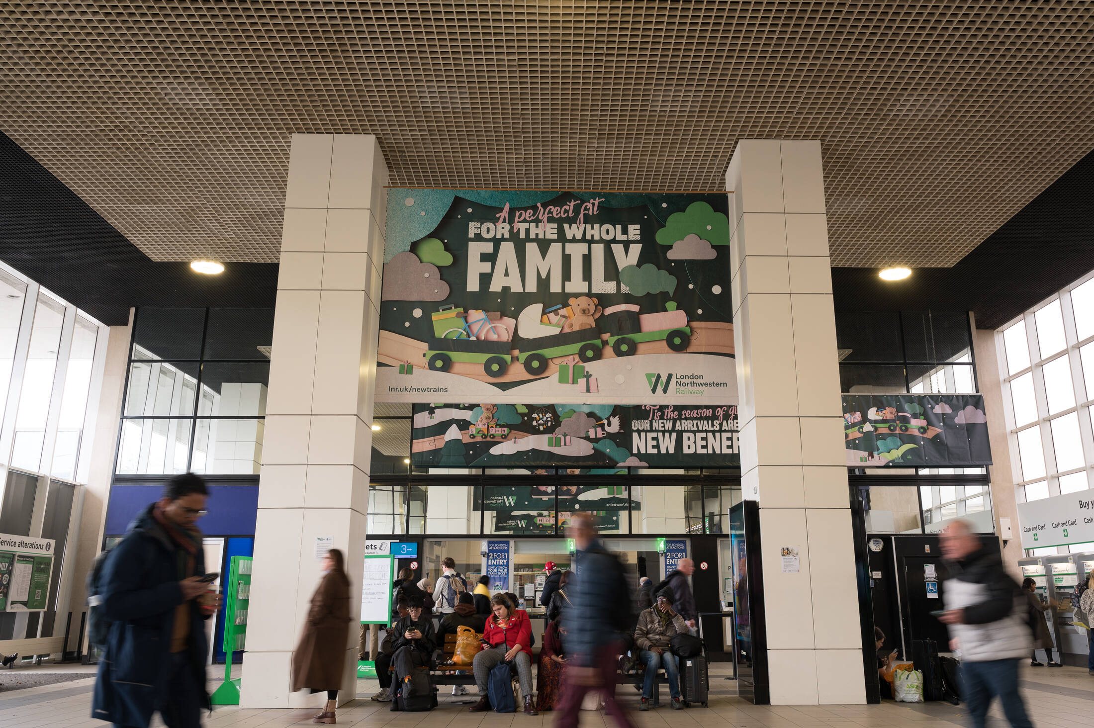 Instalación del tren Class 730 emergiendo de una caja de regalo gigante en la estación de Milton Keynes